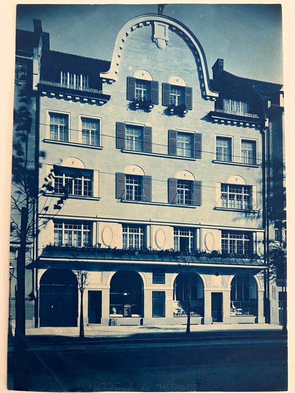 Historische Fotografie (blau getönt): mehrgeschossiges Wohnhaus mit Giebel, Fensterläden und Rundbögen im Erdgeschoss