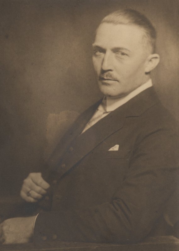 Porträtfotografie: Hubert Ritter im dunklen Anzug mit Einstecktuch, Halbfigur, sepiafarben