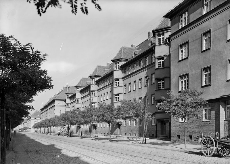 Straßenflucht mit mehrgeschossigen Wohnblocks mit Walmdächern und Erkern, Straßenbäume, Straßenbahngleise