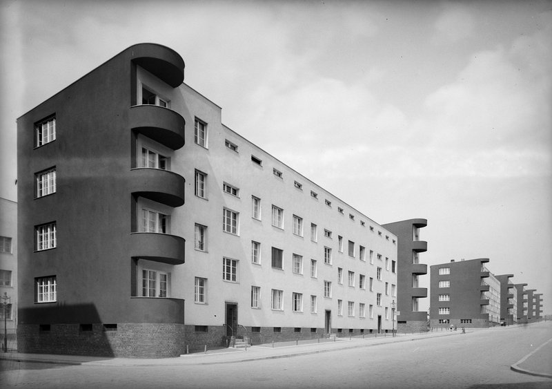 Langgestreckter Flachdach-Wohnblock mit runden Eckbalkonen, dahinter weitere Zeilenbauten mit Balkontürmen