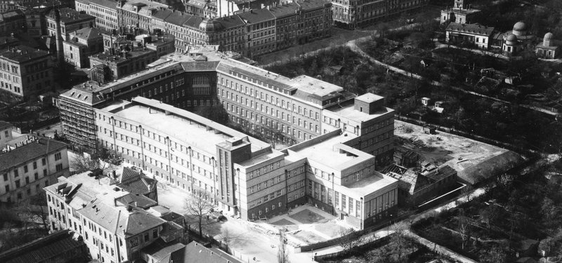 Luftaufnahme einer Vierflügelanlage mit Innenhof und Dachterrassen, umgeben von weiteren Klinikgebäuden