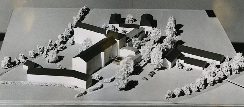 Weißes Architekturmodell einer Krankenhausanlage mit Flügelbauten und Modellbäumen; Schwarz-Weiß-Foto